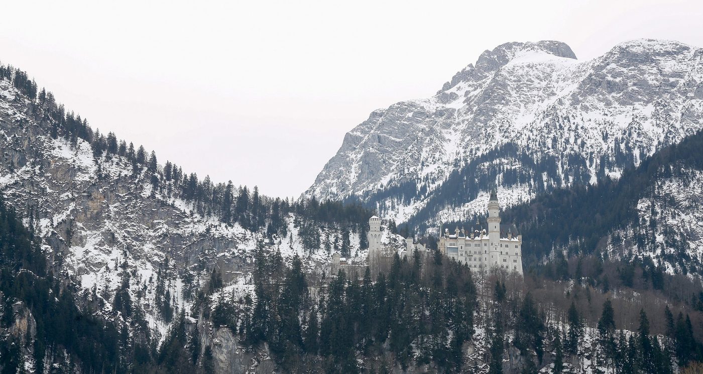 Neuschwanstein Castle in snow below the mountains